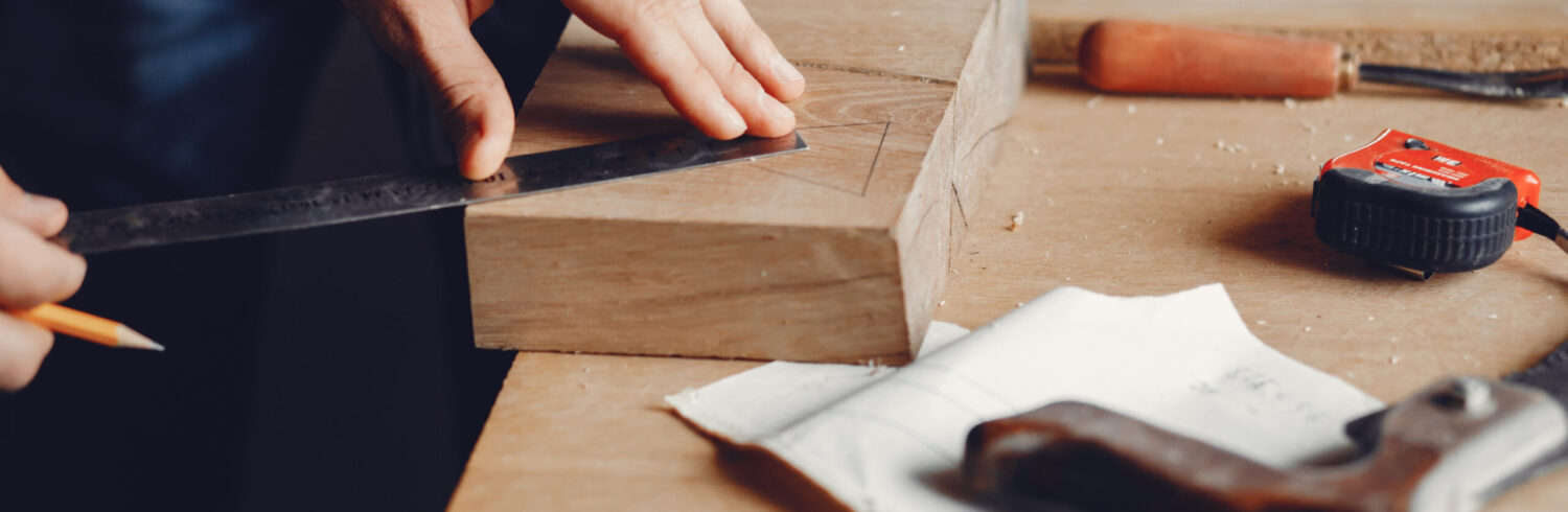 A man carves a tree. The carpenter works with a drill in a studio. An engineer provides a tree shape